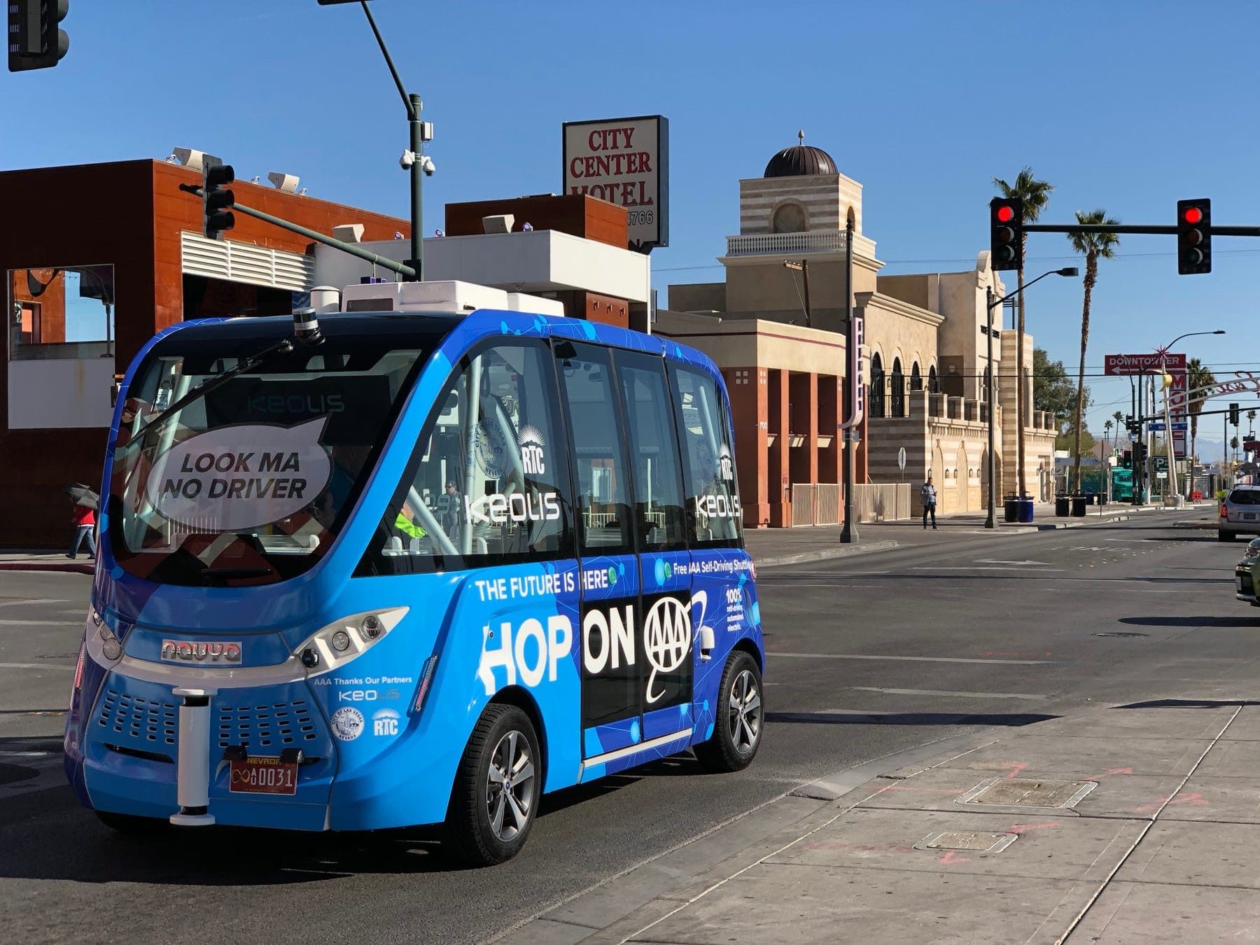 Blue AAA-branded Navya autonomous shuttle at a downtown Las Vegas intersection, windscreen sign reading Look Ma No Driver